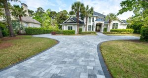 Paver driveway leading to a well‑kept home with lush landscaping, showing strong curb appeal and added home value.